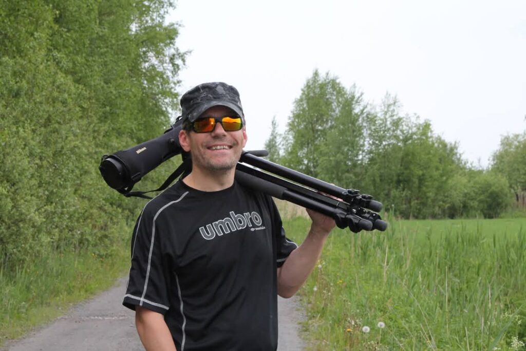 Mies hymyilee kameraan aurinkolaseissa