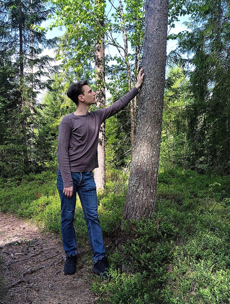 Mies nojaa puuhun toisella kädellään