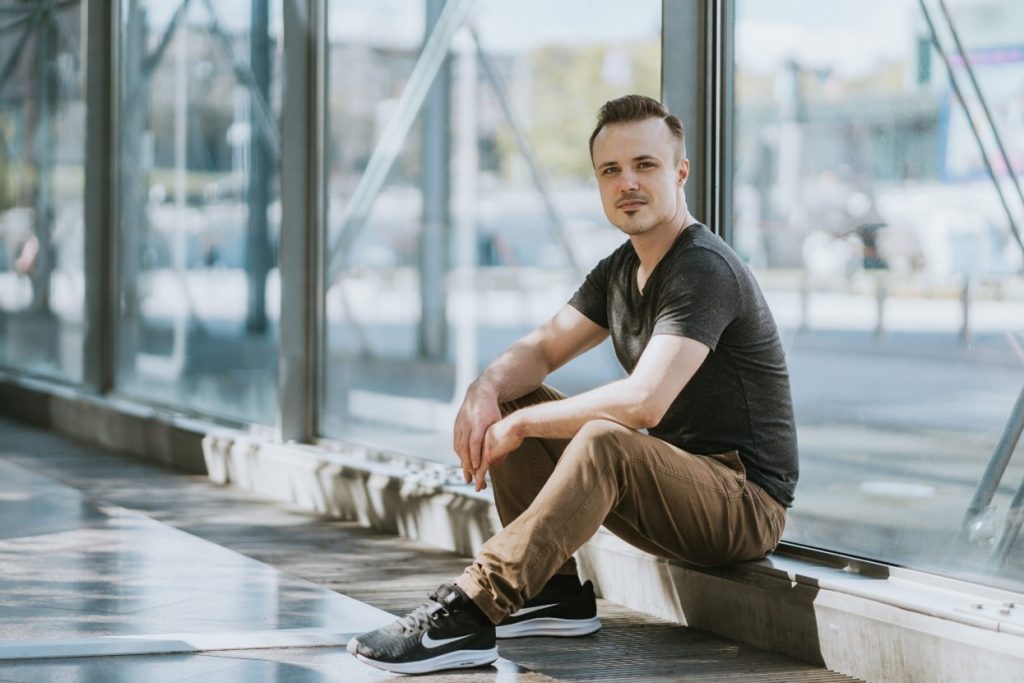 Mies istuu ja katsoo kameraan